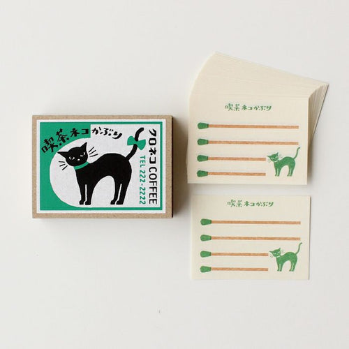 Matchbox set with black cat illustration and green text on a white background